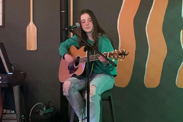 Clodagh Conboy playing guitar and singing into a microphone