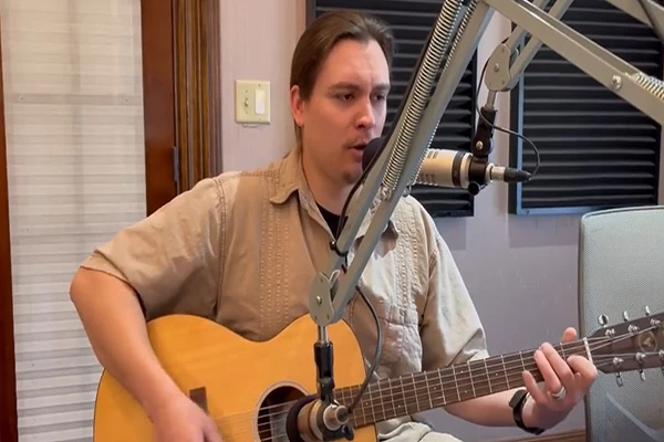 Cody James playing guitar in front of a microphone