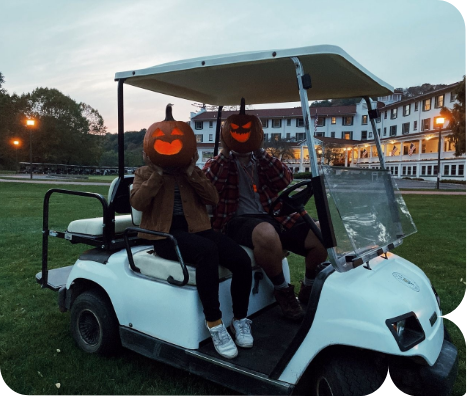 two people in a golf cart with pumpkins