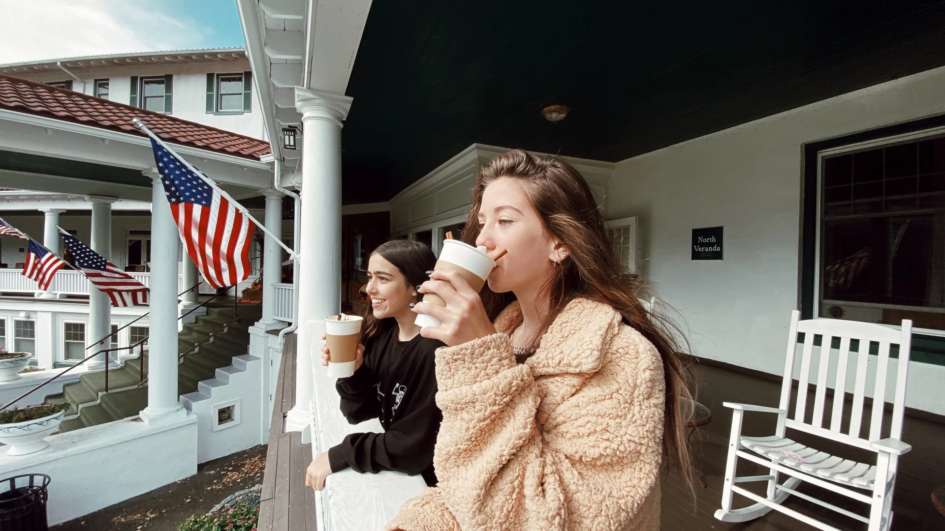 a group of women drinking from cups on a porch
