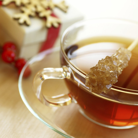 a cup of tea with a brown sugar on a stick