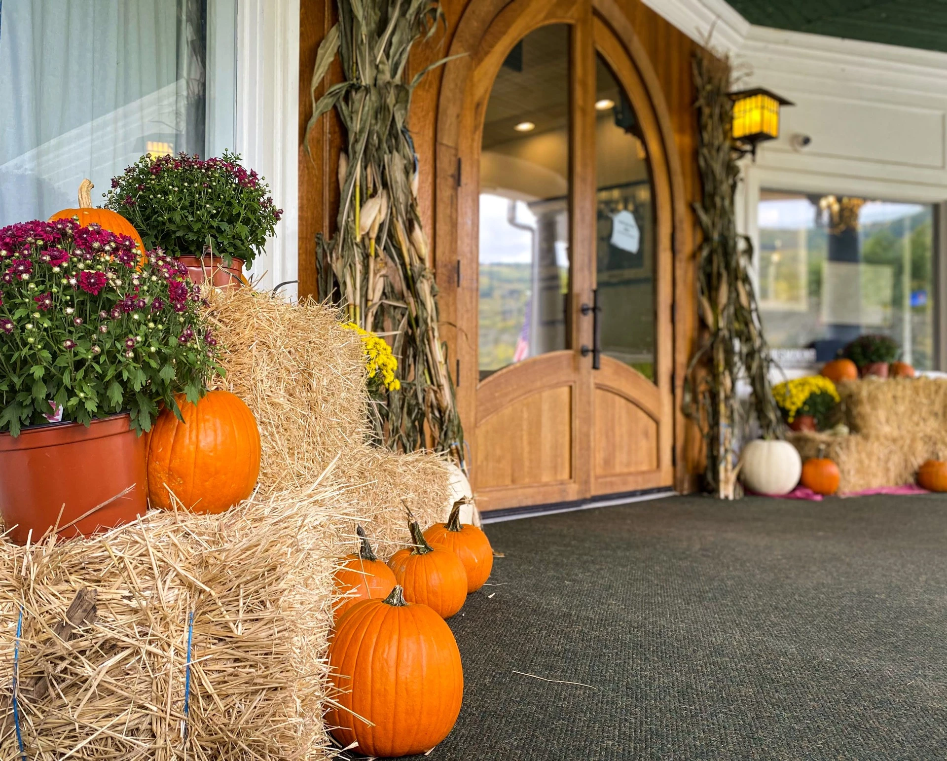 pumpkins and flowers on bales of hay outside a building