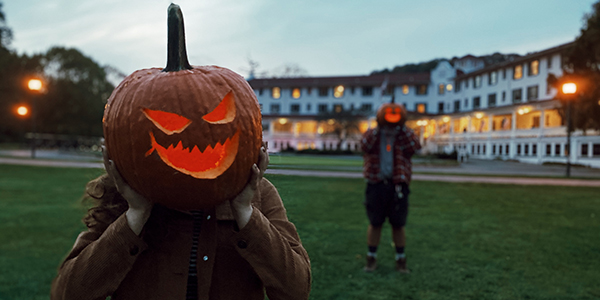 a person holding a pumpkin with a carved face