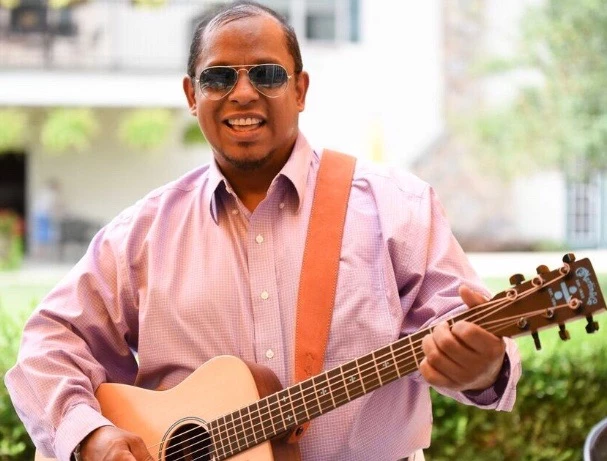 Performer, Roy Ramos wearing sunglasses and playing a guitar