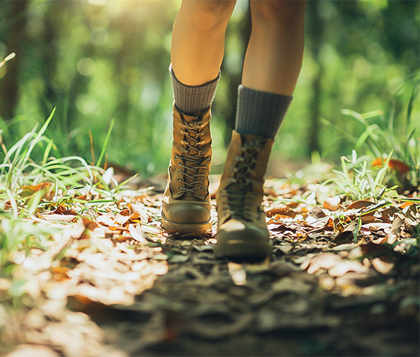 a person's legs in boots on a path in the woods