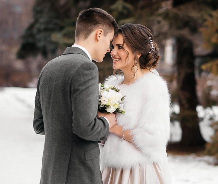 a man and woman in a white dress and fur coat