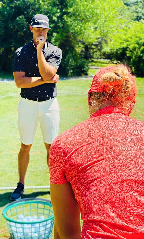 a man in a red shirt and white shorts standing on a grass field