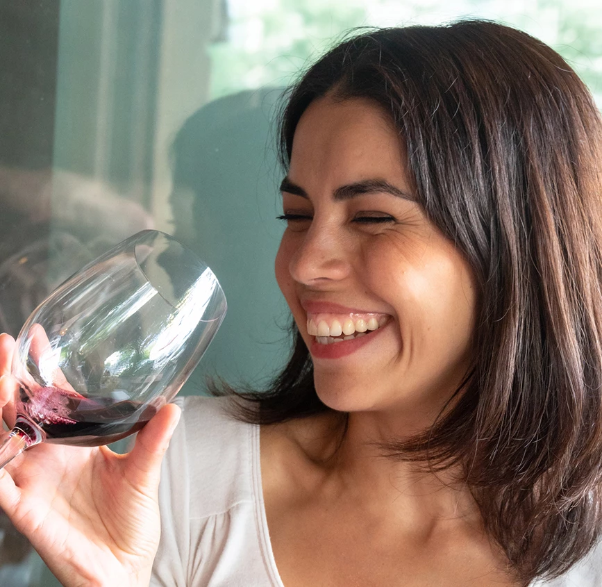 a woman smiling and holding a glass of wine