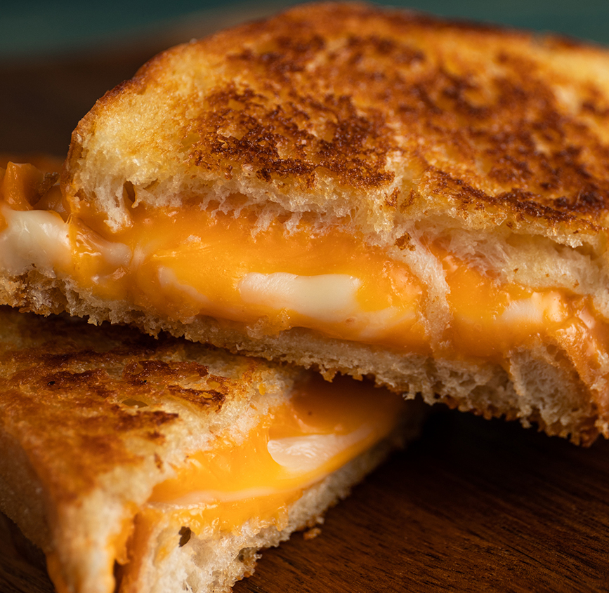 a grilled cheese sandwich on a wood surface