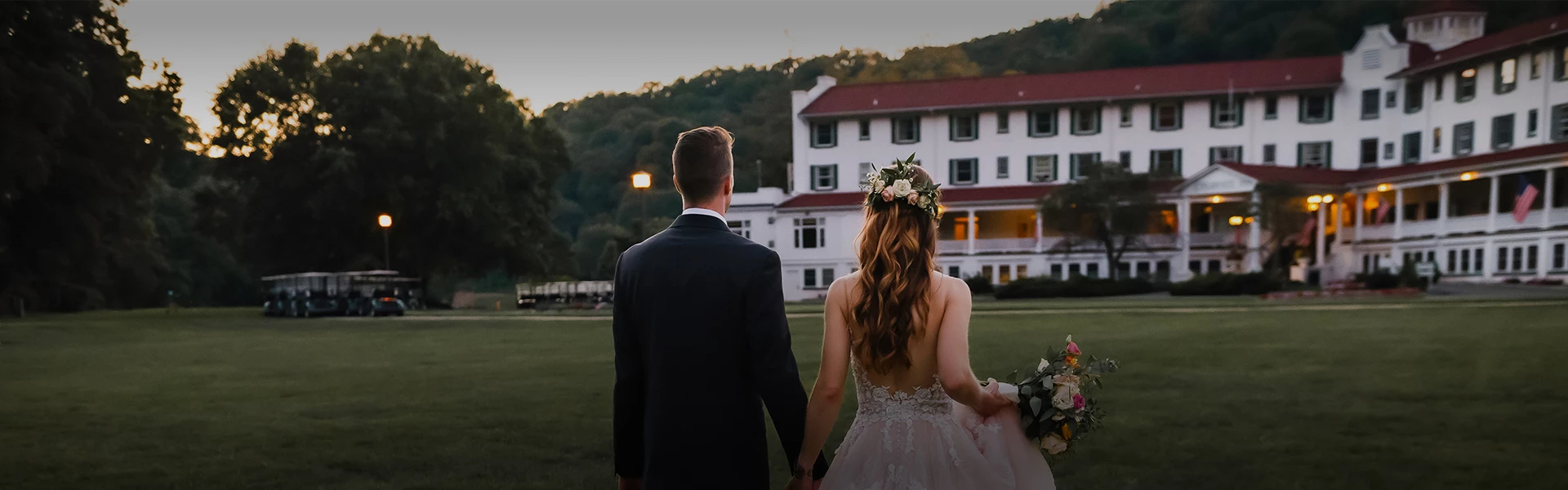 a man and woman holding hands and walking in front of a white house