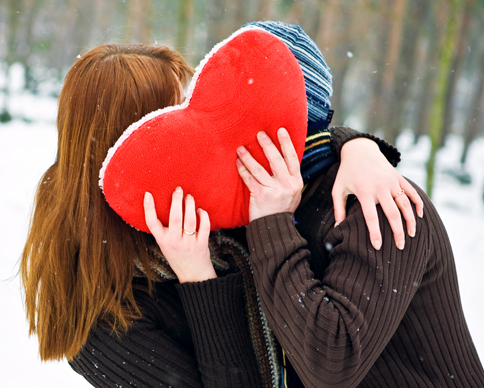 a man and woman holding a heart shaped pillow