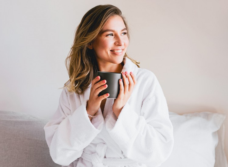 Woman in a robe in bed holding coffee mug