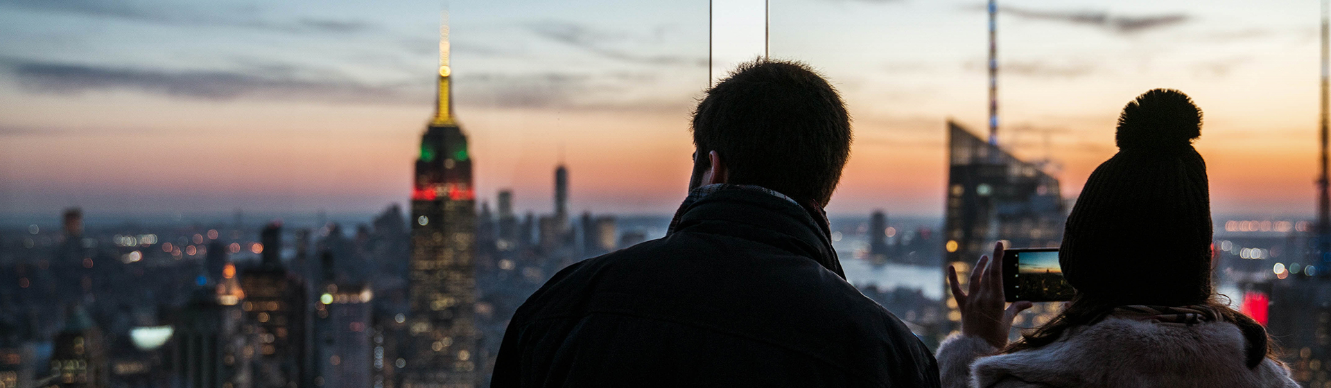 A couple taking a photo of the city skyline at sunset