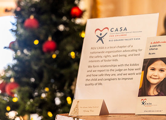 a sign with a picture and a christmas tree in the background