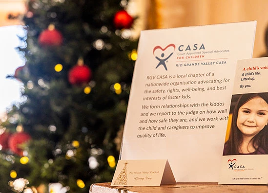 a sign with a picture and a christmas tree in the background