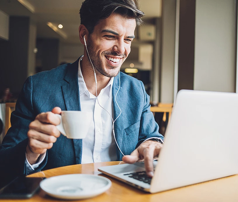 man drinking coffee and looking at a computer 