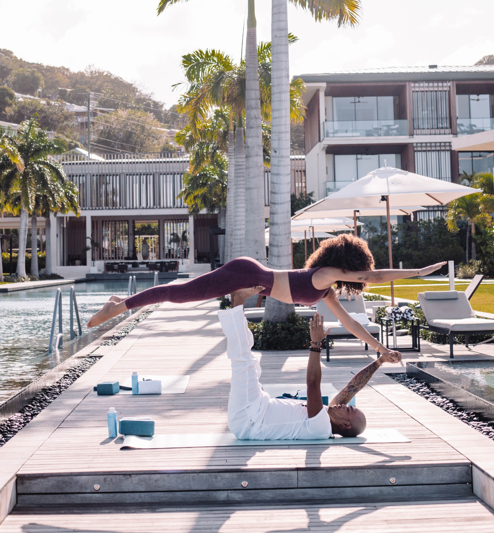 a man and woman doing acrobatic exercises on a dock near a pool