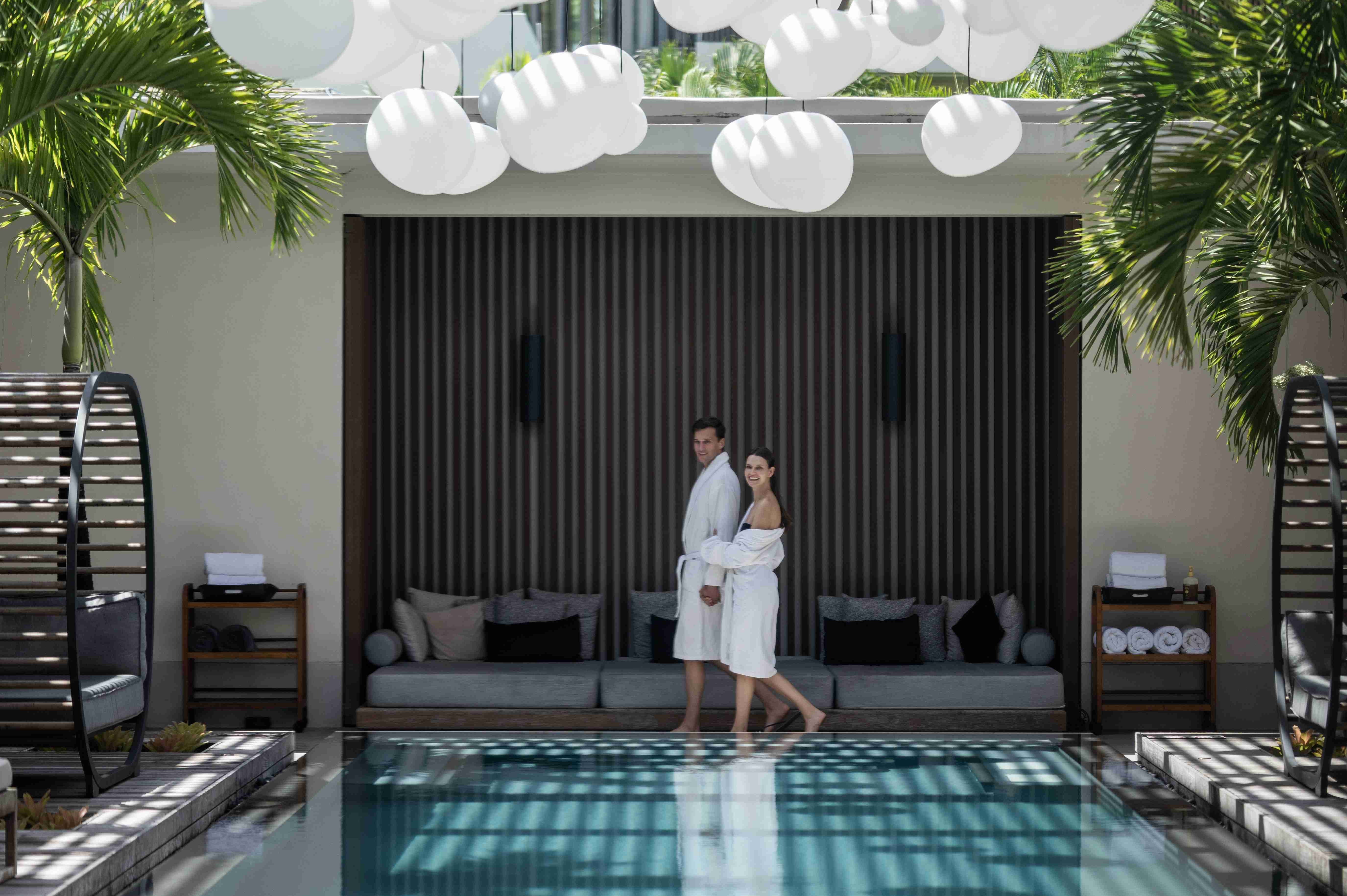 a man and woman in white robes standing in front of a pool