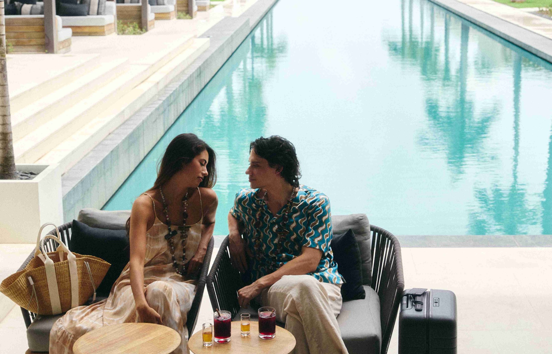 a man and woman sitting on a chair by a pool