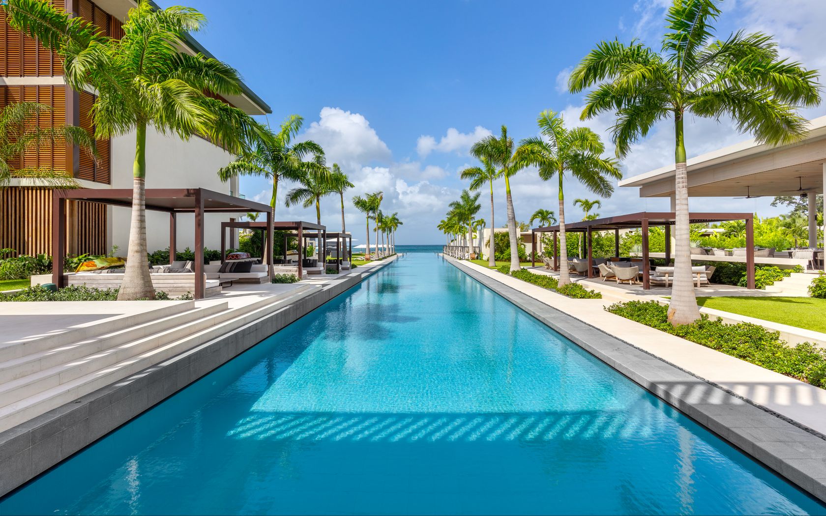 a long pool with palm trees and a building