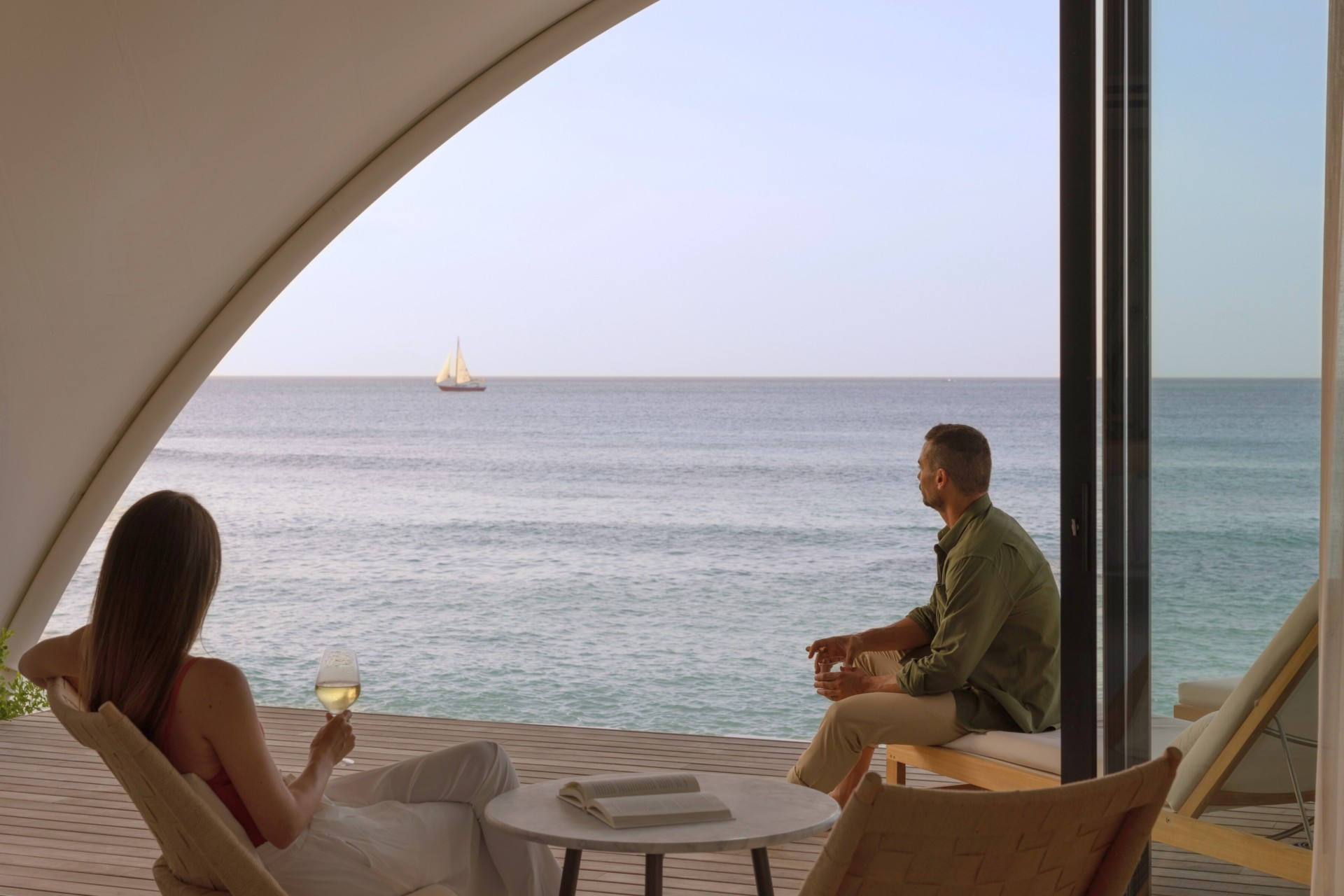 a man and woman sitting on a deck overlooking a body of water