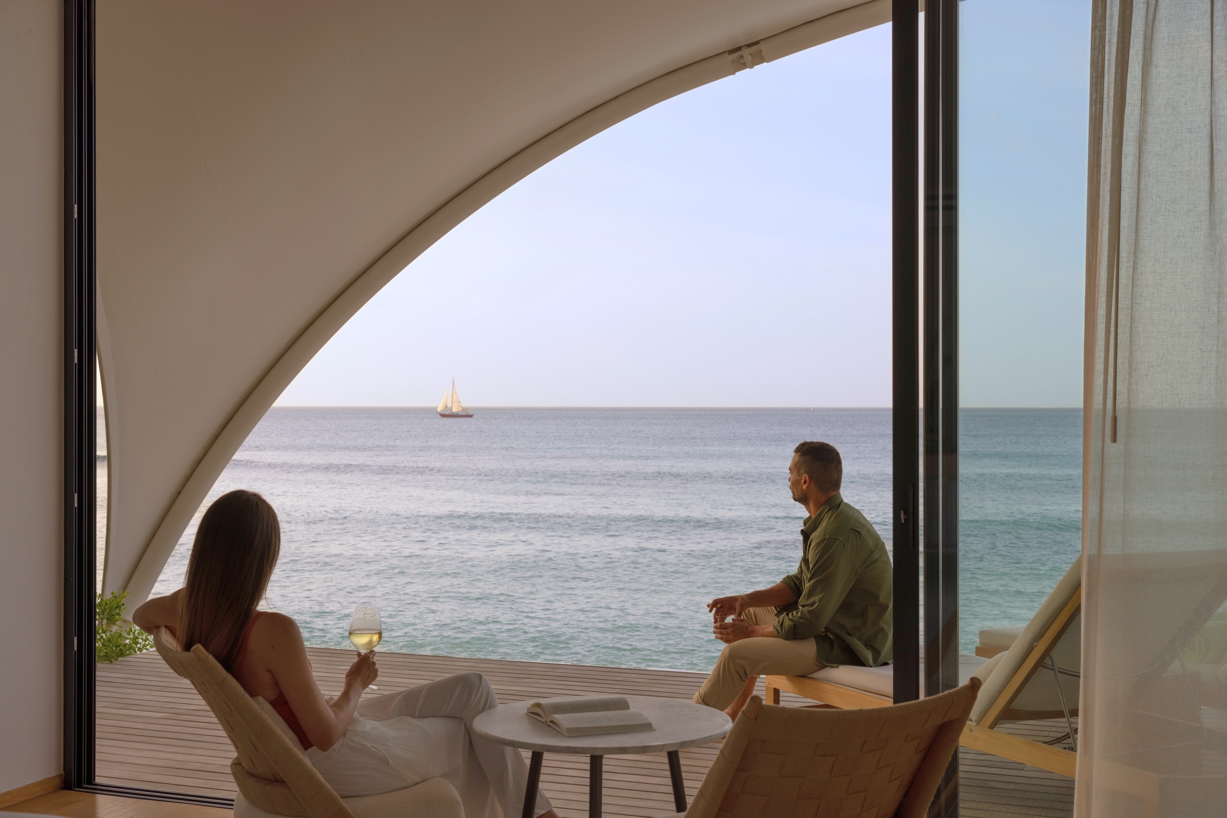 a man and woman sitting on chairs by the ocean