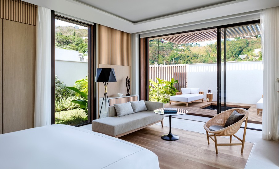 The interior of a bedroom at a luxury villa in Grand Anse, showing a bed, sofa and round table.