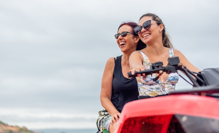 a couple of women riding a red car on a sunny day