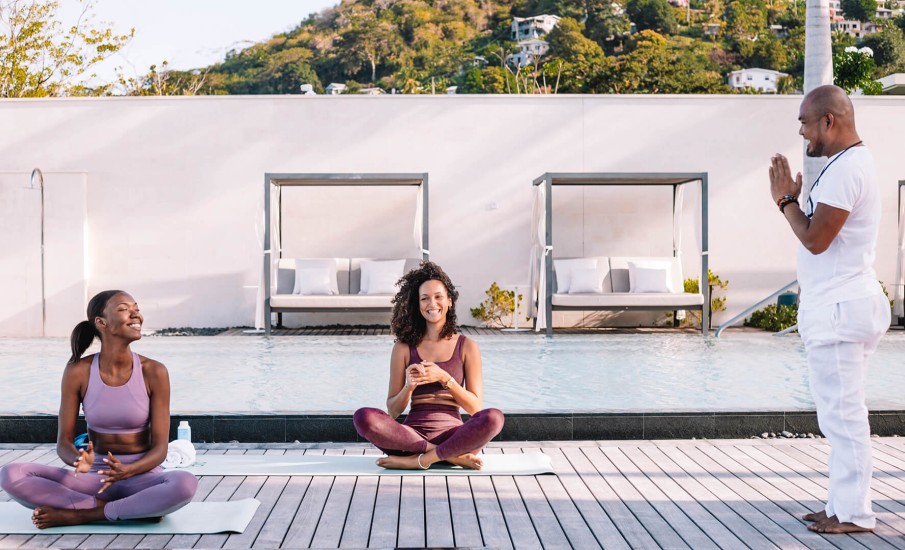 a man and a woman sitting on mats by a pool