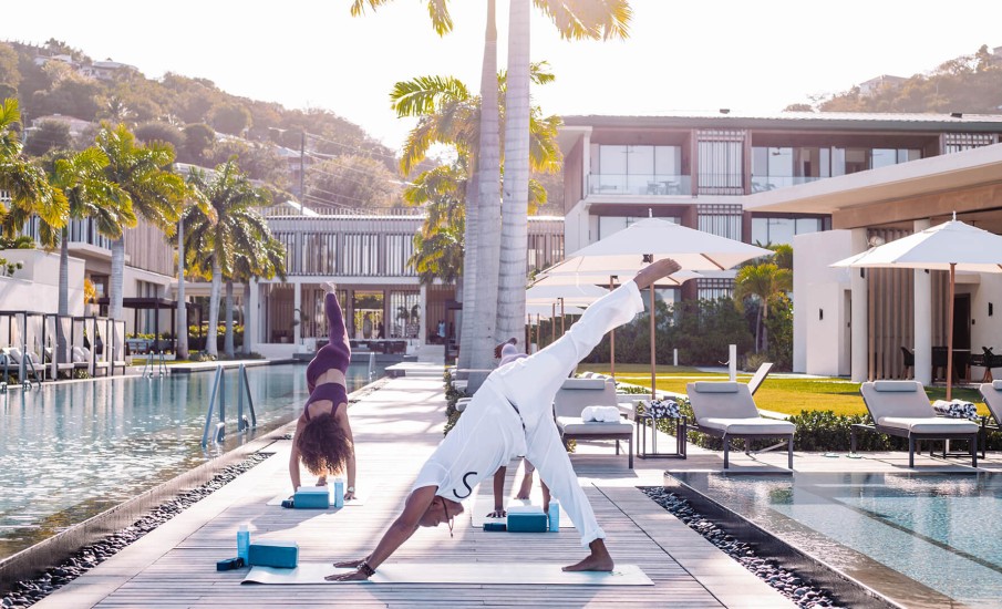 a couple of people dancing by a pool with a building in the background