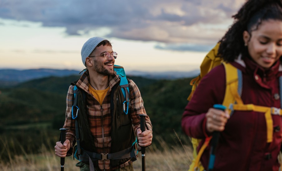 a man and woman standing in a field with a valley in the background