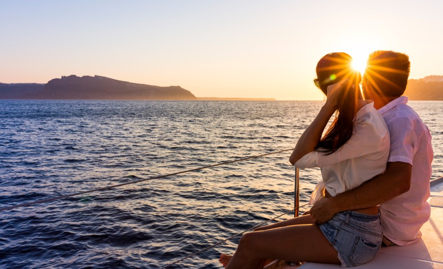 a man and woman kissing on a dock over water