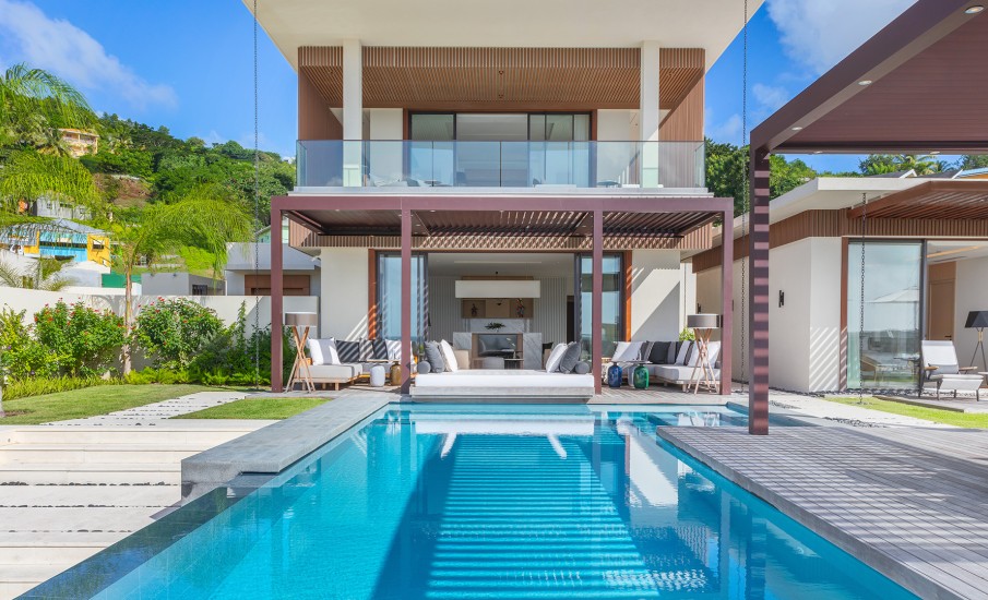 Exterior of a two-story villa at Silversands Grand Anse in Grenada with a glass balcony and private pool.