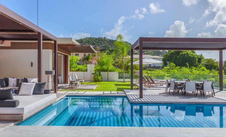 A private pool and patio with lounge chairs outside of a luxury villa in Grand Anse.