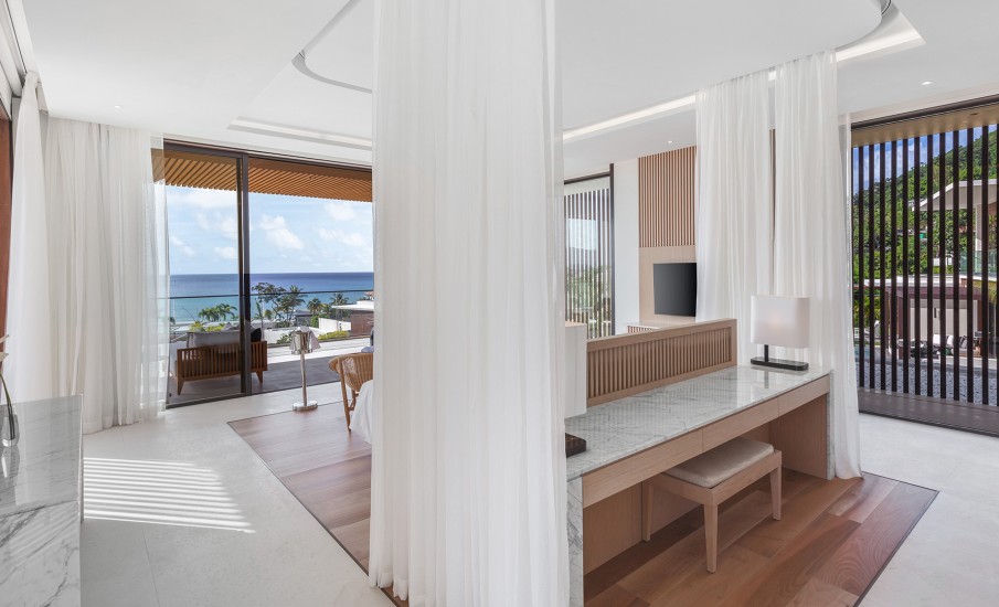 Interior of a luxury villa in Grenada showing a marble desk table with lamps and white privacy curtains.