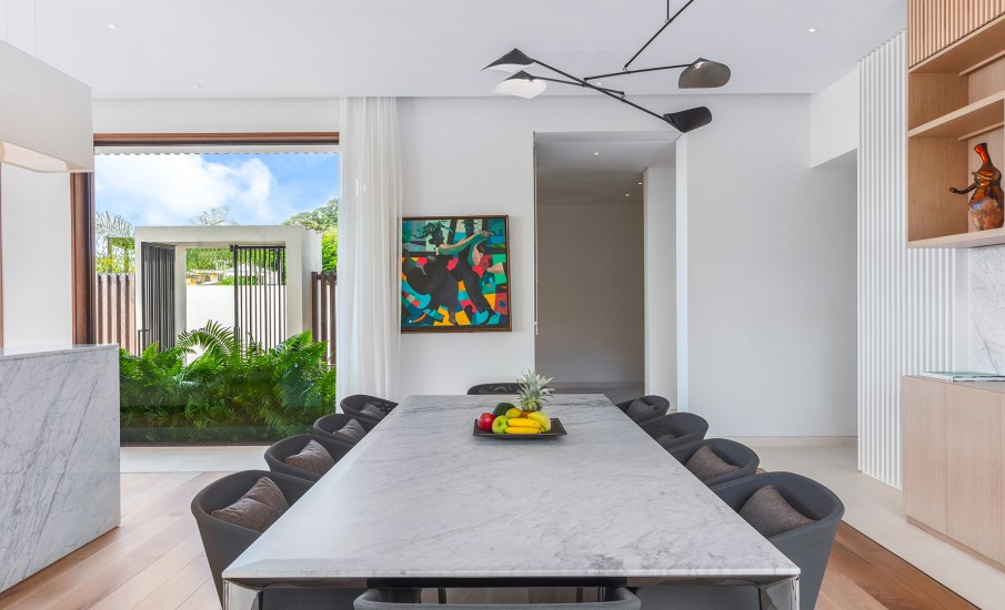 The interior dining room of a villa in Grenada showing a marble dining table topped with a bowl of fresh fruit, surrounded by black chairs.