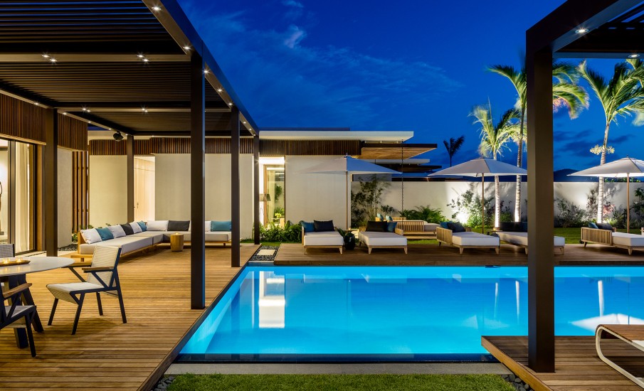 A private swimming pool illuminated at night in front of a luxury villa in Grand Anse.