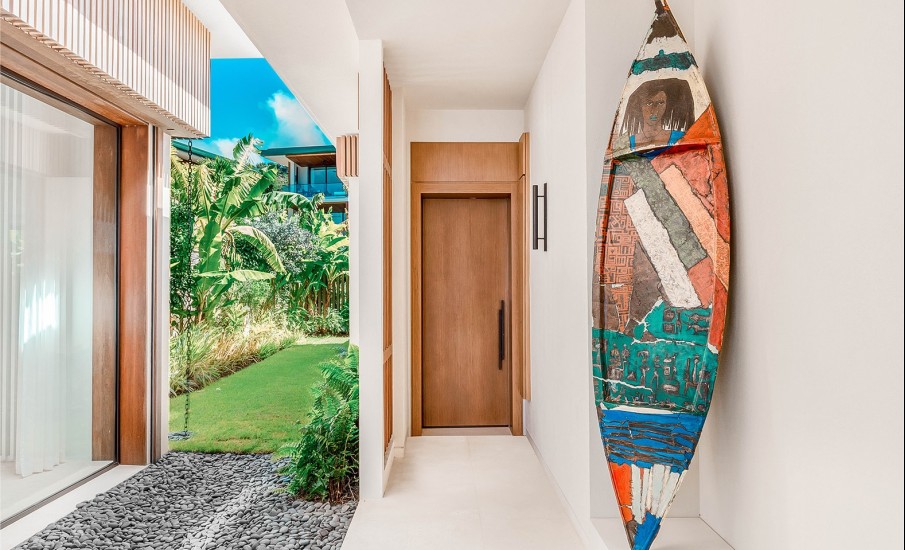 A hand painted surfboard propped up against the wall of the entrance to a luxury hotel suite in Grendada at Silversands Beach House.