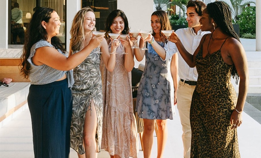 A group of young women and a man enjoying martini cocktails at an outdoor bar in Grenada at Silversands Beach House resort.