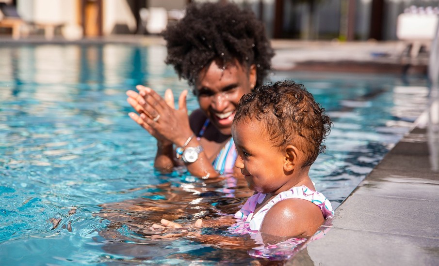 A woman swimming with her young daughter in a pool at Silversands Beach House Resort in Grenada.