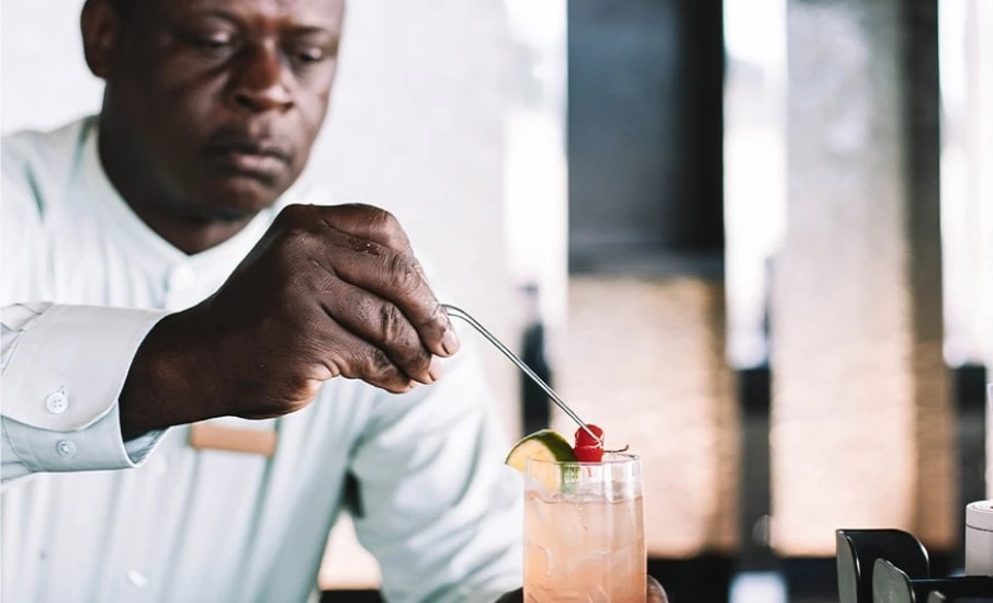 A bartender garnishing the top of a craft cocktail with a lime and cherry at Beach House Resort in Grenada.