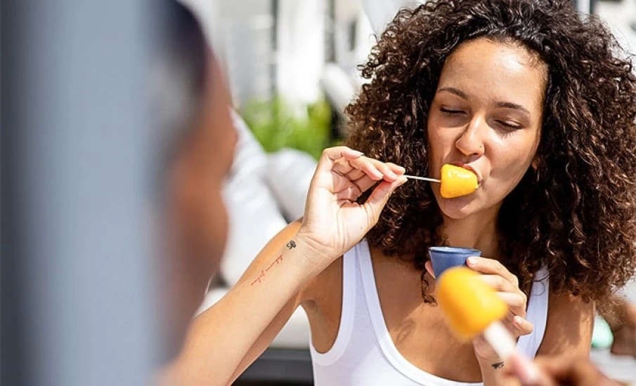 A woman eating a yellow popsicle at Beach House luxury Hotel in Grenada.											