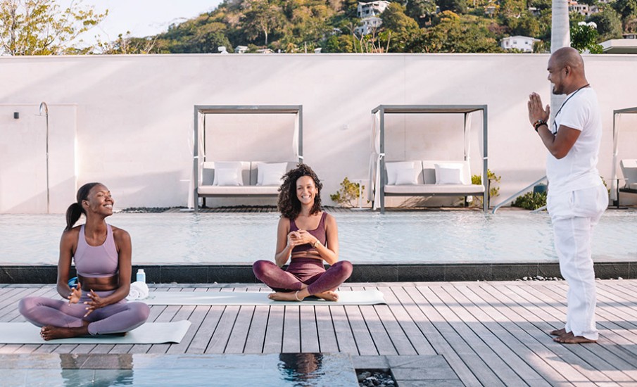 a woman sitting on a mat next to a man standing on a dock