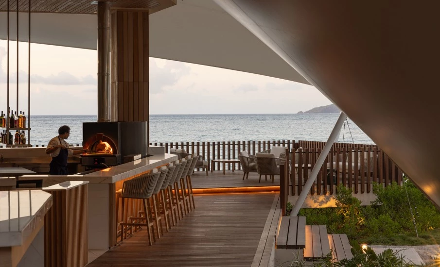 a patio with chairs and a wood deck overlooking the water