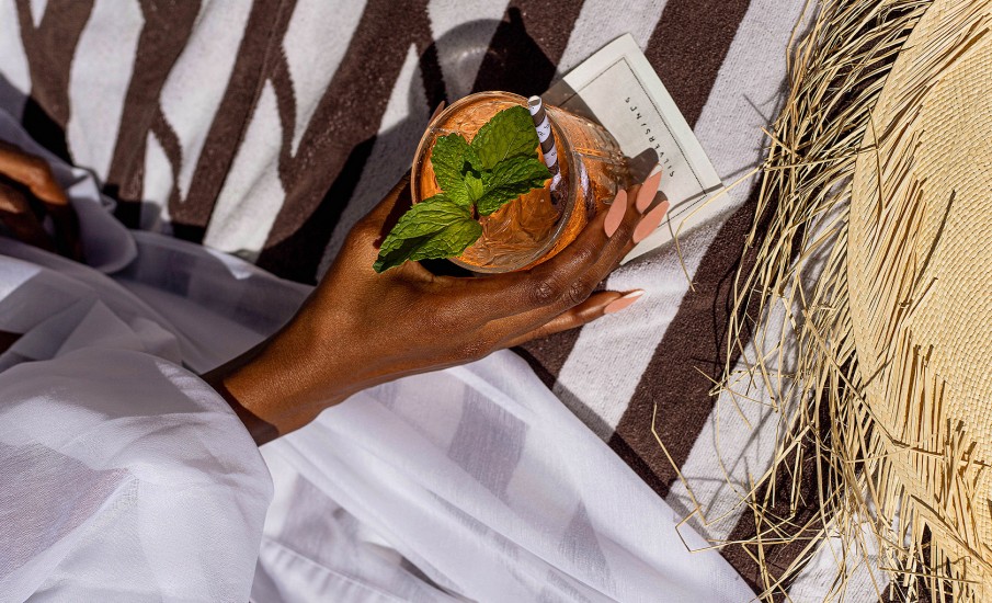 Close up of a womans hand holding a drink garnished with mint at a bar in Grenada at Silversands Grand Anse resort.