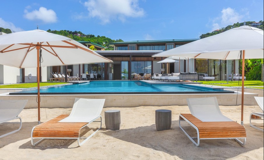 Two beach chairs on the sand in front of a private pool villa in Grenada at Silversands Grand Anse Beach Resort.
