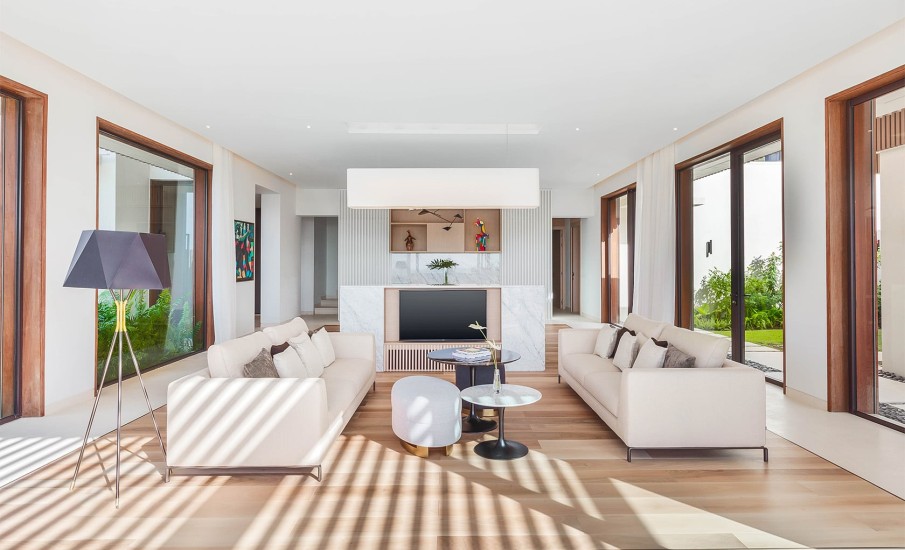 The interior of a luxury villa in Grenada shows couches in a living room area with a TV and natural light coming in from large windows at Silversands Grand Anse Resort.
