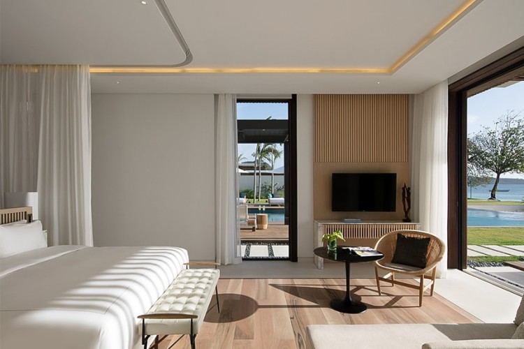 A bed with white sheets and a white privacy curtain at a villa at Silversands Grand Anse resort.