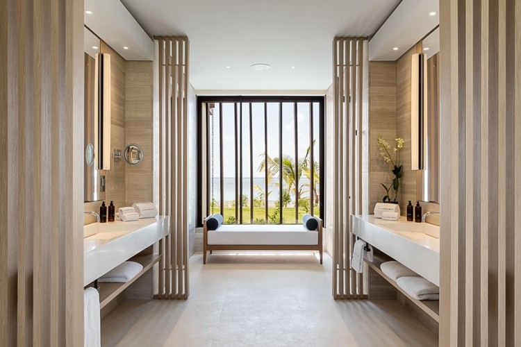 A bathroom with marble sinks and a large window at Silversands Grand Anse resort.