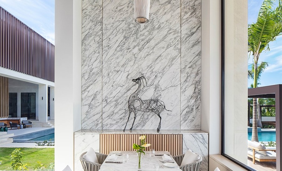 A dining table next to a marble wall where a wire sculpture of a horse is displayed at Asiatique in Grenada.